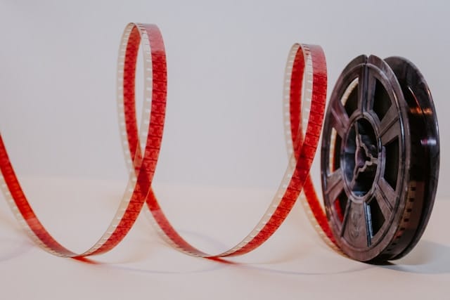 A spiral of celluloid film coming off a reel. The film is red against a bright white background.