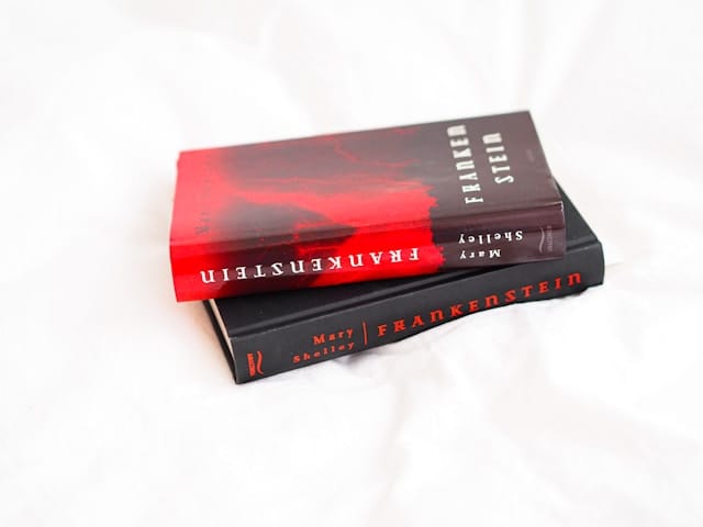 Two copies of Frankenstein by Mary Shelley sit one on top of the other on a white background. The top copy has a red and blac