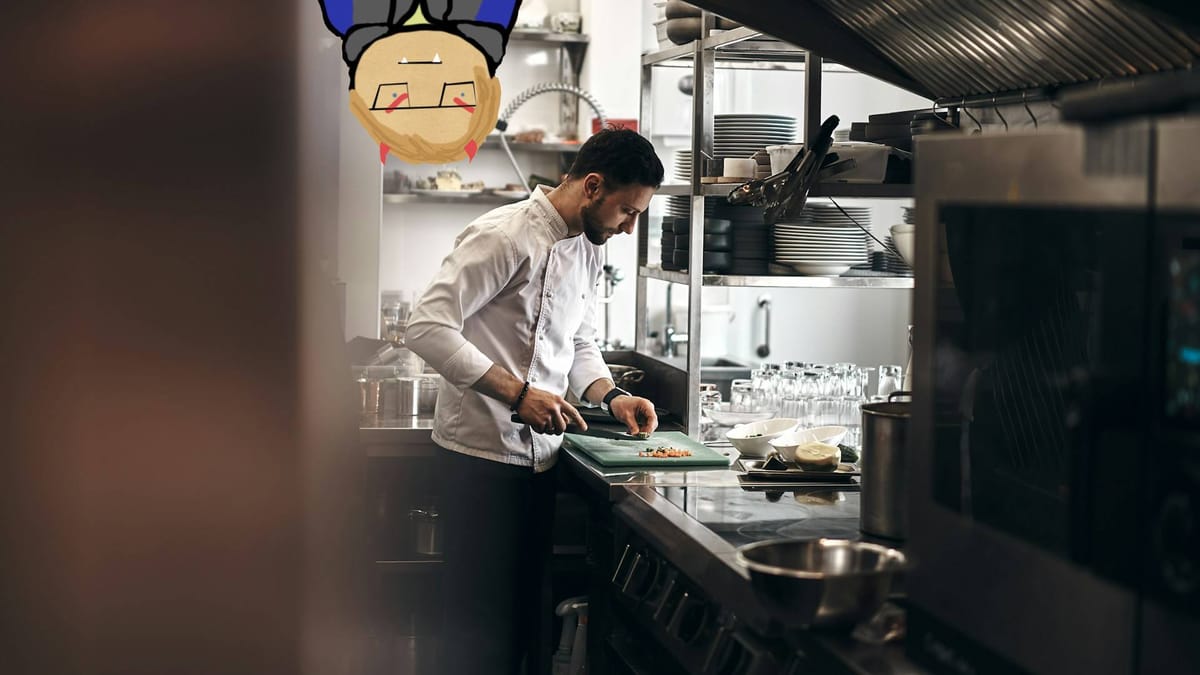 A chef works in a commercial kitchen chopping vegetables. A caricature of the author peeks down from the ceiling like a bat.